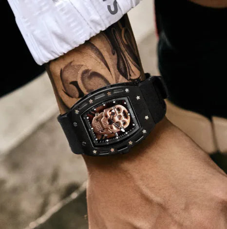 Black wristwatch with intricate design on a tattooed arm
