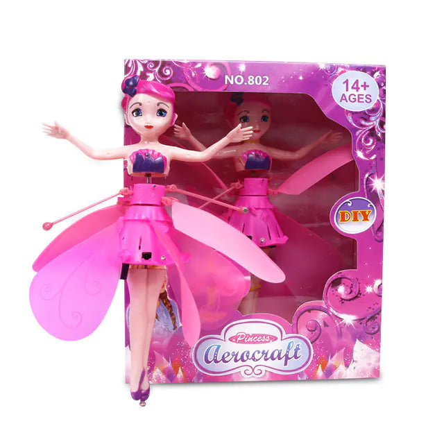 Pink fairy doll with open wings in front of its packaging on a white background