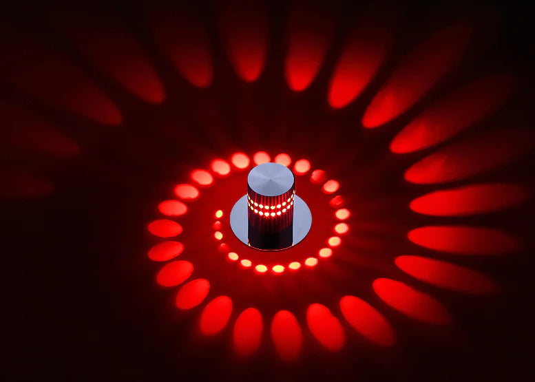 Red circular light fixture with a central cylindrical component on a dark background