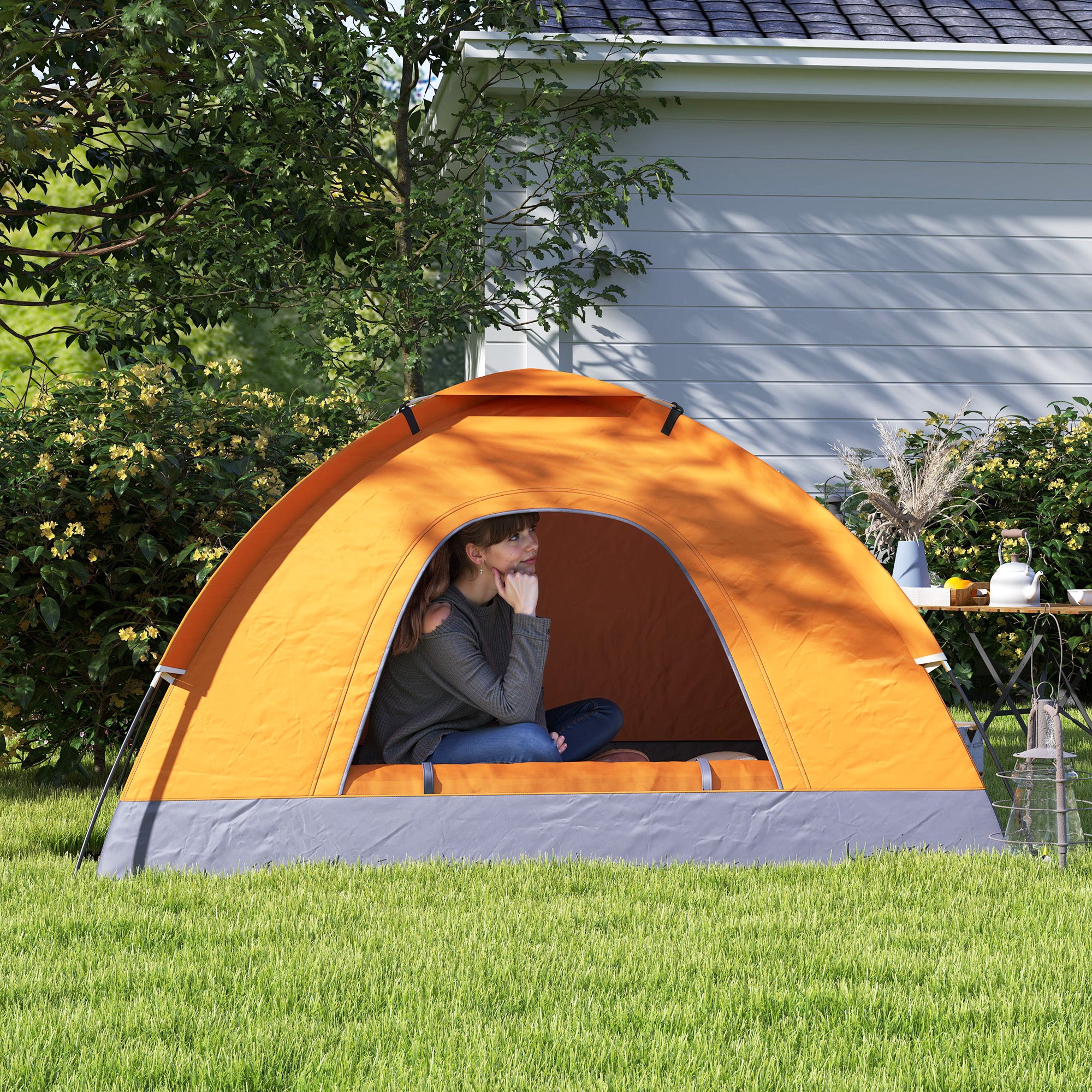Person sitting inside an orange and gray tent in a backyard setting