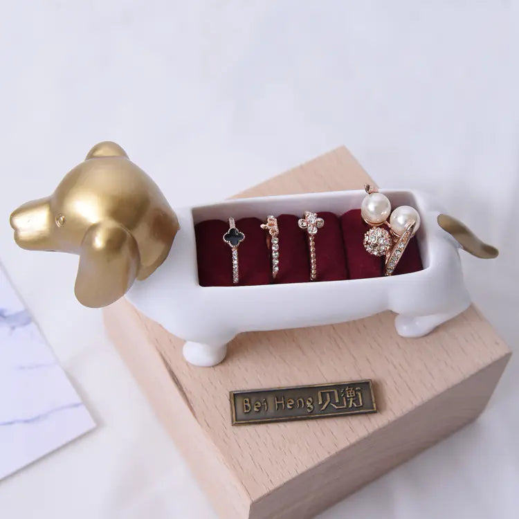 Dog-shaped jewelry holder with rings on a white background