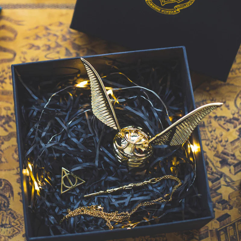 Gold snitch with wings open in a decorative box on a patterned surface
