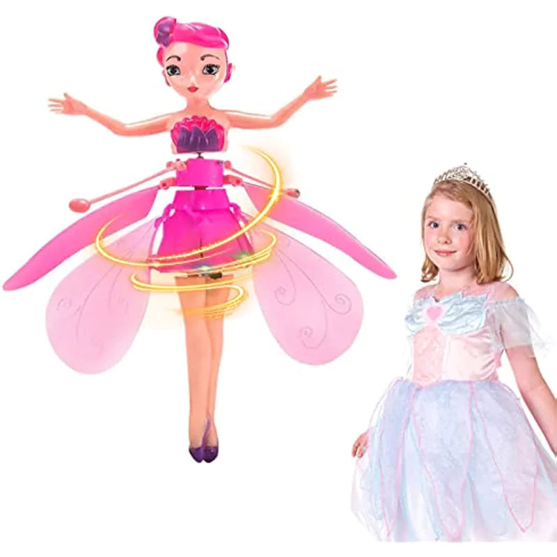 Toy fairy figure with pink hair and wings next to a young girl in a princess dress on a white background